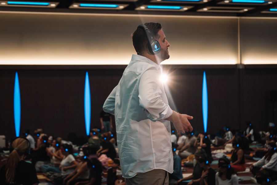 Profile shot of Alexis in over-ear headphones addressing an audience with flame lights in the background